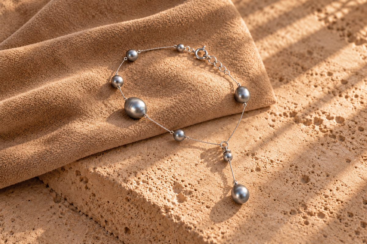 Complete grey pearl station bracelet with clasp and dangling pearls on warm suede and stone.