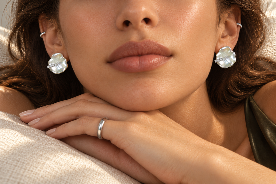 Baroque pearl earrings with a diagonal sparkling strip, worn in a front-facing close-up.