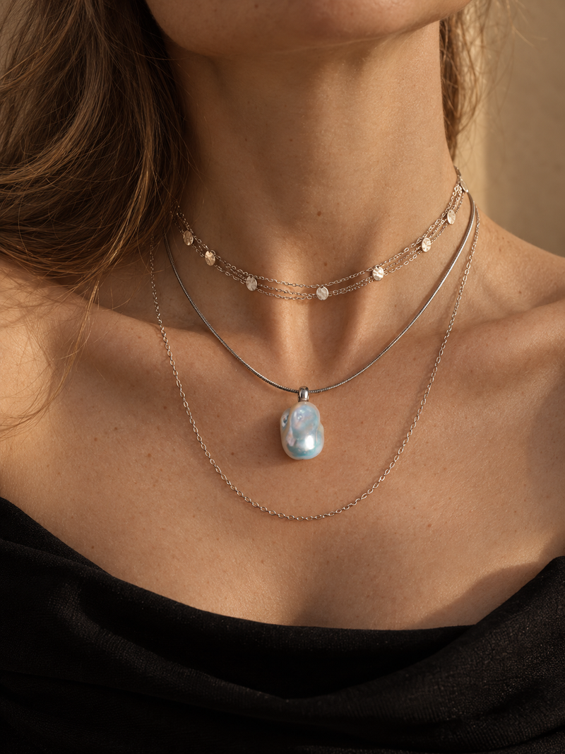 Layered pearl necklaces at the neckline in golden sunlight