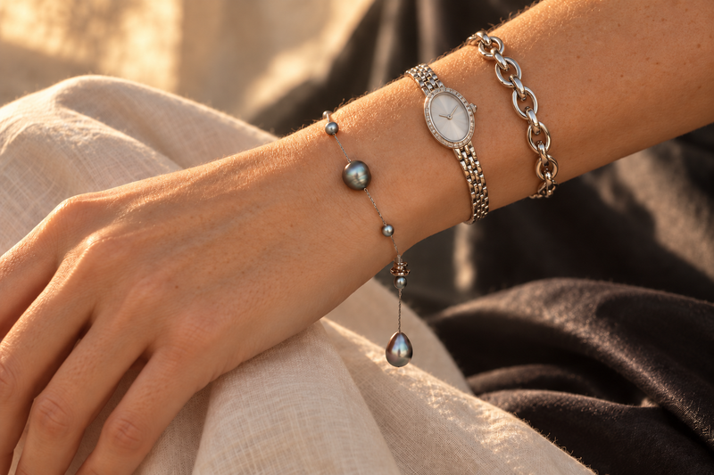 Grey pearl station bracelet worn at the wrist in golden sunlight